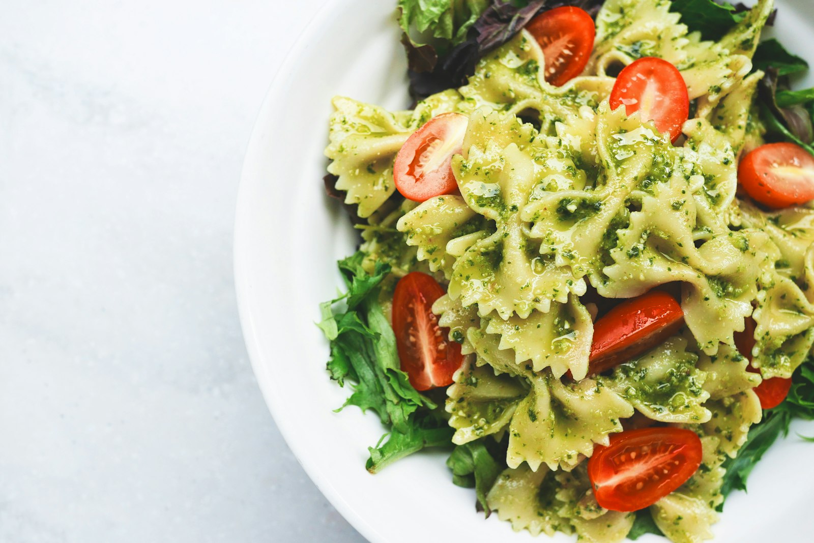 A bowl of pasta with fresh herbs and olive oil on a wooden table